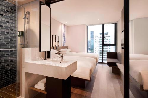 首尔首尔费尔菲尔德客栈酒店的浴室设有两张床、一个水槽和镜子