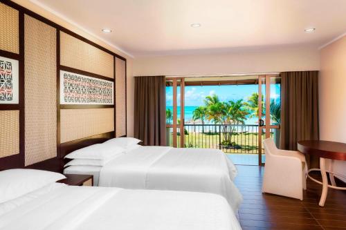 Mulifanua萨摩亚海滩喜来登度假村的酒店客房设有两张床、一张桌子和一个阳台。