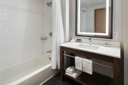 奥尔巴尼Four Points by Sheraton Albany的一间带水槽、浴缸和镜子的浴室