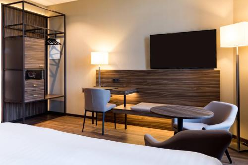 美因茨AC Hotel by Marriott Mainz的酒店客房设有一张床、一张书桌和一台电视机。
