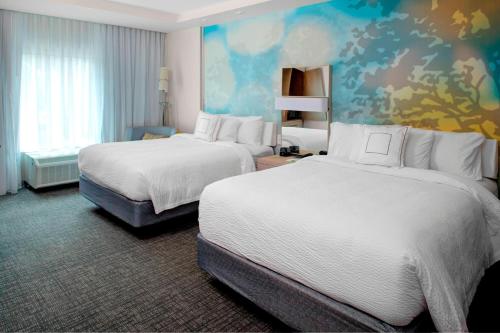 肯尼索Courtyard by Marriott Atlanta Kennesaw的酒店客房设有两张床,墙上挂有绘画作品