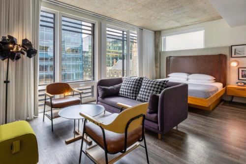 华盛顿Moxy Washington, DC Downtown的酒店客房配有一张床、一张沙发和椅子。