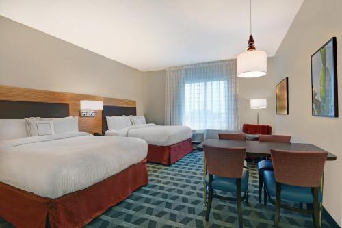 布雷登顿TownePlace Suites by Marriott Sarasota/Bradenton West的酒店客房设有两张床和一张桌子。