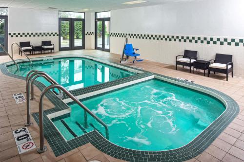 阿普尔顿Four Points by Sheraton Appleton的游泳池位于酒店客房内,配有椅子和桌子