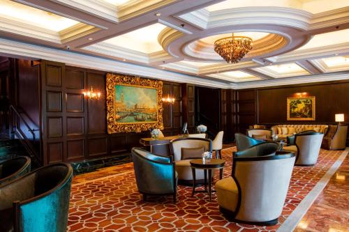 吉隆坡The Ritz-Carlton, Kuala Lumpur的一间带桌椅和吊灯的餐厅