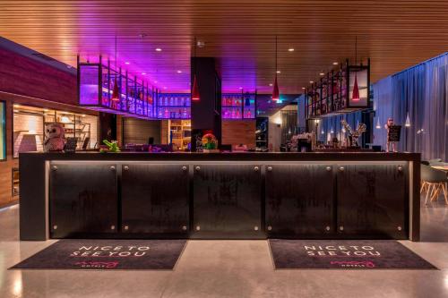 美因河畔法兰克福慕奇夕法兰克福机场酒店的餐厅内的酒吧拥有紫色的灯光