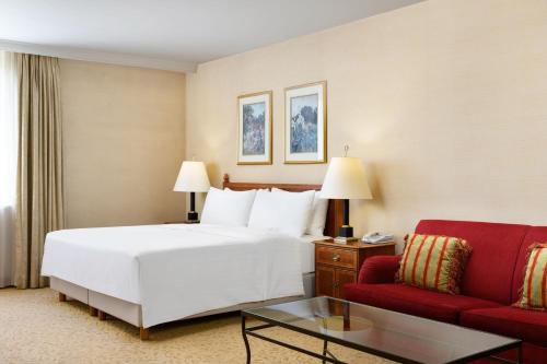布达佩斯布达佩斯千禧万豪行政公寓的酒店客房,配有一张床和一张红色的沙发