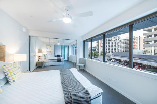 布里斯班Link Portside Wharf Apartment Hotel的一间卧室设有一张大床和大窗户
