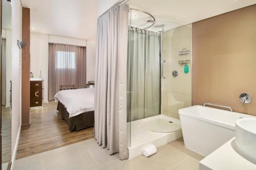 肯普顿帕克OR坦博普罗提酒店的一间带浴缸和淋浴的浴室以及一张床