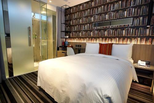 台北丰居旅店-忠孝馆的卧室配有白色的床和书墙
