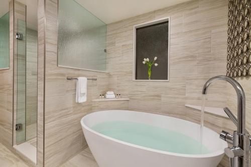 海伦娜Delta Hotels by Marriott Helena Colonial的带浴缸和玻璃淋浴间的浴室。