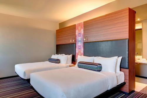 亚松森亚松森雅乐轩酒店的配有白色枕头的酒店客房内的两张床