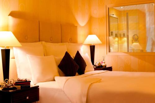 阿特劳阿特劳万丽酒店&度假村的一间卧室配有一张带两盏灯的大型白色床。