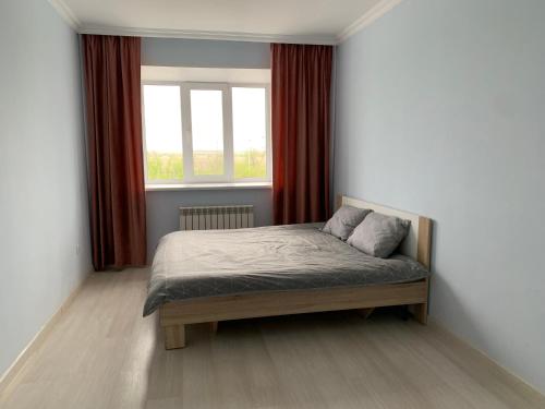 阿克托比Апартаменты в районе Болашак的一间卧室配有床和红色窗帘的窗户