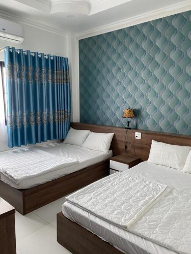 朱笃Kim Ngân Motel的一间卧室设有两张床和蓝色的墙壁