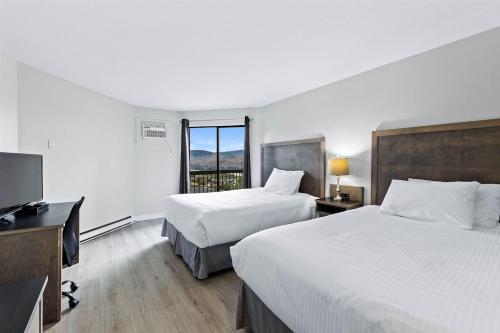坎卢普斯The Vista Inn的酒店客房设有两张床、一张桌子和一台电视。