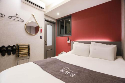 首尔Hotel dongyangjang Dongdaemun-Jongno的卧室配有白色的床和红色的墙壁