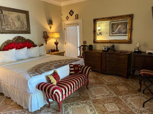 土桑El Amador Inn Downtown Tucson的一间卧室配有一张床、一把椅子和镜子