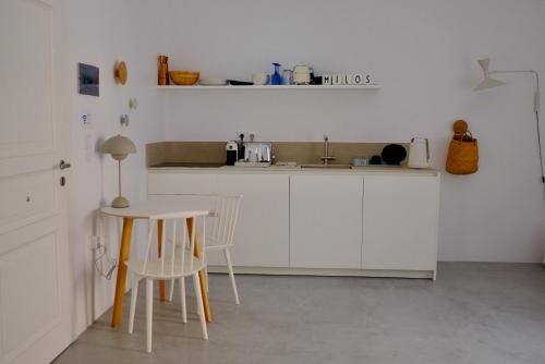 阿波罗尼亚MILORA SuNSET的厨房配有白色橱柜和桌椅