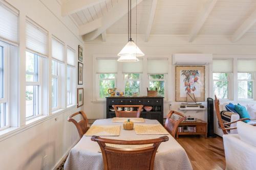 凯卢阿Sunshine Cottage just steps to Kailua beach的一间带桌子和一些窗户的用餐室
