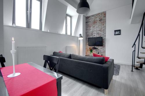 克拉科夫Apartament Romantyczny Zamkowa15的客厅配有黑色沙发和红色桌子