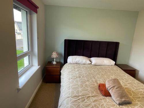 爱丁堡3 bed house with parking near airport的一间卧室配有带两个枕头的床和窗户
