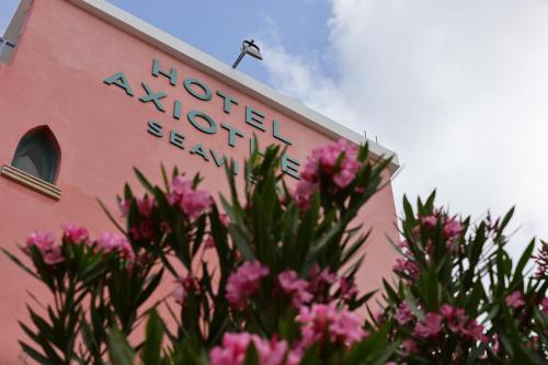 帕福斯阿克希奥迪亚酒店的粉红色的建筑,上面有粉红色花卉的标志