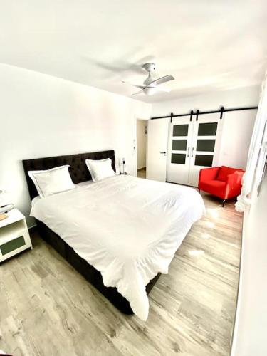 圣费尔南多Apartamento en el centro San Fernando Cadiz.的卧室配有白色的床和红色椅子