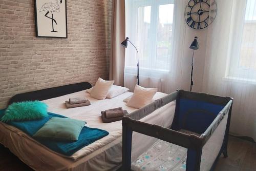 比得哥什Przytulne studio w centrum Starego Miasta的一间卧室配有带枕头的床铺和时钟