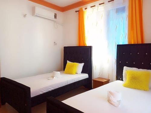 姆特瓦帕Homestay Luxurious apartments with swimming pool的客房设有两张带黄色枕头的床和窗户。
