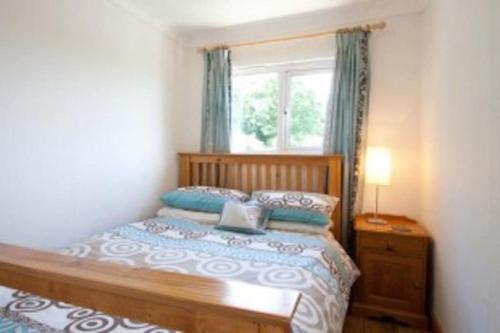斯旺西Summercliffe Chalet No 75的一间卧室配有一张木床和窗户