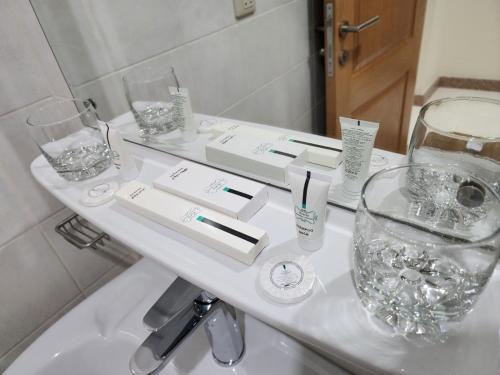 达曼S Maskan Hotel的白色浴室台面,配有玻璃杯和水槽