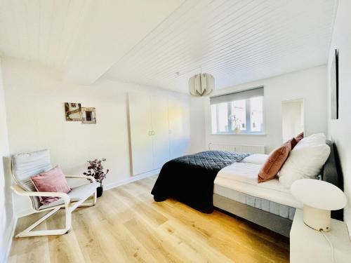 腓特烈港aday - Charming apartment in the pedestrian street of Frederikshavn的白色卧室配有床和椅子