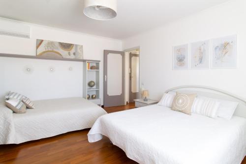 托瓦尼亚Attico Centralissimo Vista Mare的卧室设有两张床,拥有白色的墙壁和木地板