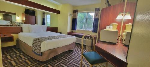 塔尔萨Microtel Inn & Suites by Wyndham Tulsa - Catoosa Route 66的配有一张床和一张书桌的酒店客房