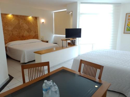 韦拉克鲁斯Angeles Suites & Hotel的酒店客房,设有两张床和一张带水瓶的桌子