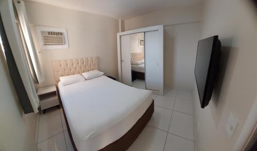 马塞约Apartamento BEIRA-MAR com 2 quartos的一间白色的小卧室,配有床和镜子