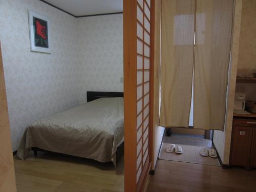 由布市湯布院 おやど花の湯yufuin oyado hananoyu的一间卧室配有一张床和一扇带拖鞋的门