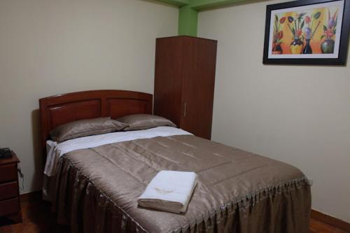 塔克纳HOTEL LUCERO REAL的一间卧室配有一张大床和木制床头板