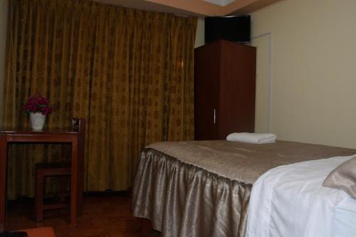 塔克纳HOTEL LUCERO REAL的一间卧室配有一张床、梳妆台和桌子