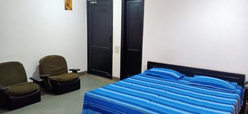 诺伊达Blessings Noida Home stay的一间卧室配有一张床和两把椅子