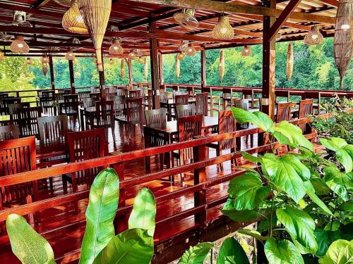 Ban OSpringRiver Resort的一间设有木椅和桌子的餐厅,种植了植物