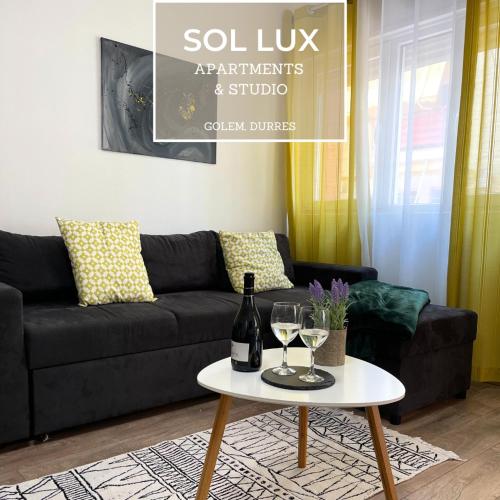 都拉斯SOL Lux Apartments 1st Floor的客厅配有黑色沙发和带酒杯的桌子