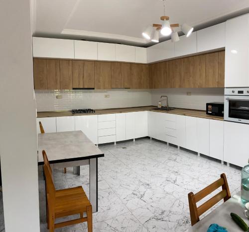 乌雷基Sunrise Ureki的厨房配有白色橱柜和桌椅