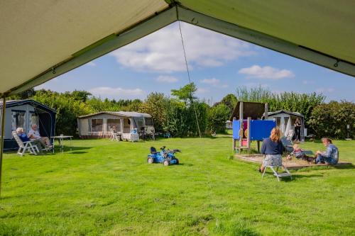 KolhamDe Veenborg的一群人坐在帐篷下的草地上