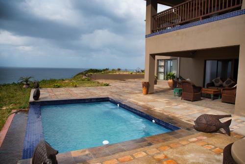 伊尼扬巴内Villa Castellos的一座位于大海房子前面的游泳池