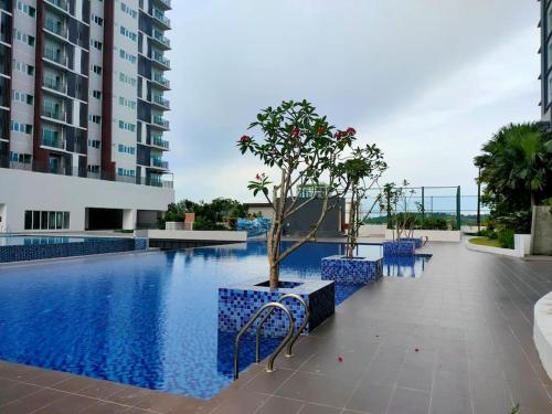 史里肯邦安MyHome S1 At Seri Kembangan With A View的一座带蓝色椅子的游泳池,一座位于大楼旁的树