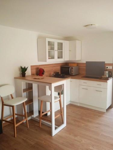 尼姆Maison d'hotes - chambre-kitchenette-salle de bain-espace extèrieur的厨房配有白色橱柜和桌椅