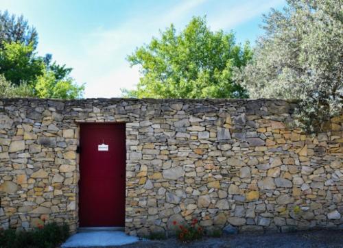 尼姆Maison d'hotes - chambre-kitchenette-salle de bain-espace extèrieur的前面有红色门的石墙