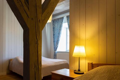 SkangaļiSkangaļu muiža的一间卧室设有两张床和一张桌子上的台灯。